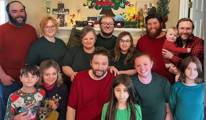 Family gathered together indoors for a holiday photo, smiling and close, taken during Steve’s final Christmas in 2022 before his passing.